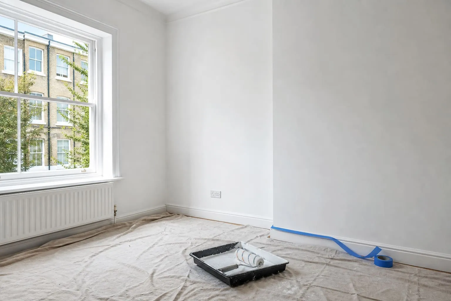 Freshly painted room with dust sheets and roller tray